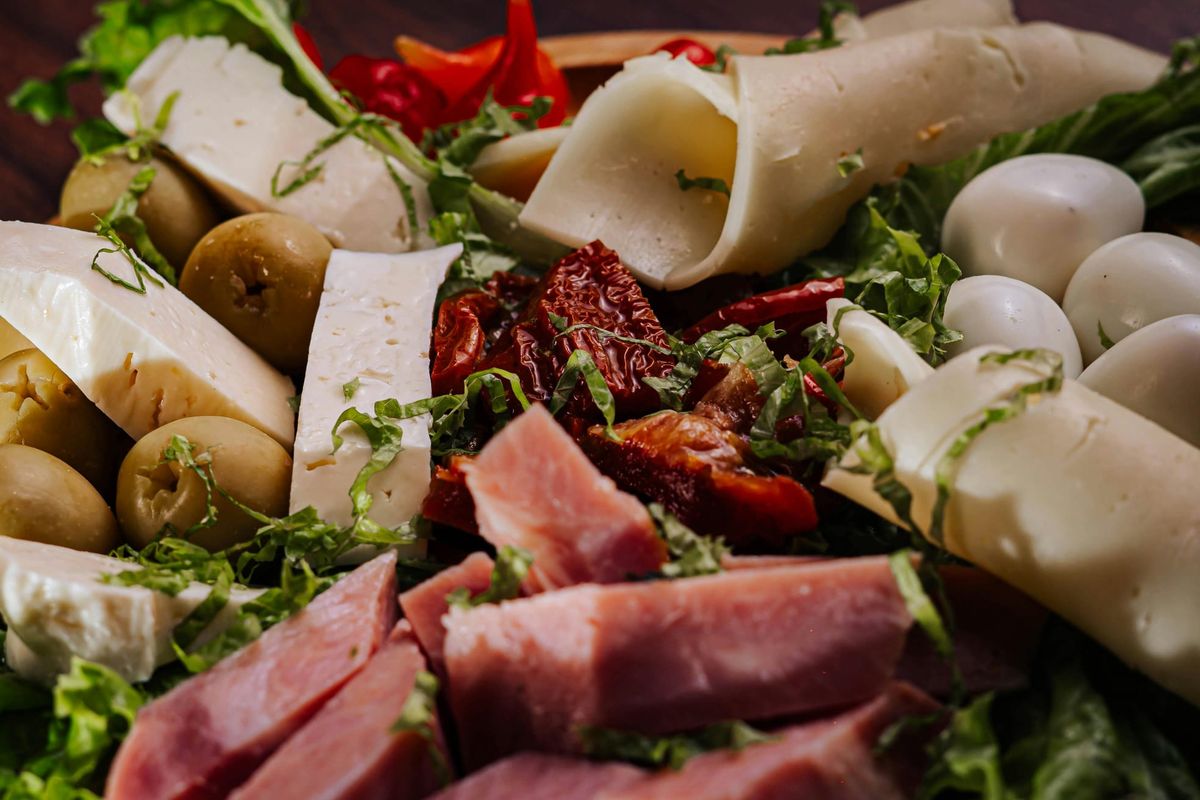 Platte mit Käse, Schinken, Oliven und getrockneten Tomaten